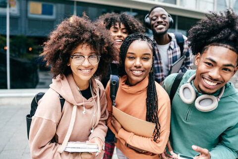 A group of Black college students standing in front of a building on a college campus.