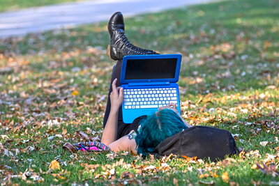 student studying on laptop on grass outside