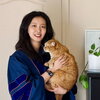Dr. Yu wearing her doctoral graduation robe and holding an orange cat