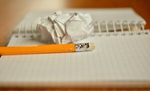 chewed pencil and crumpled paper sitting on blank notebook