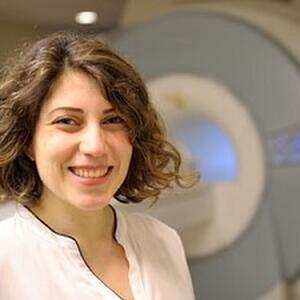 Sepideh Sadaghiani standing in front of MRI machine