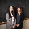 Jiawen Wu standing on left side, Eva Pomerantz on right, in front of a black board with mathematical formulas written all over it.