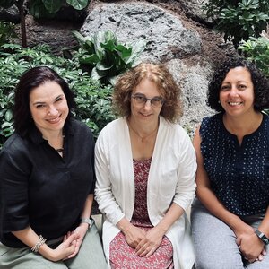 From left to right, Professors Tancredy, Travis, and Shenouda sitting together in front of the plants housed in the Psychology building atrium