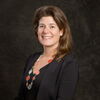 Eva Pomeranz profile picture. Smiling with a dark cardigan sweater in front of a dark background