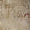 White chalk on concrete pillar with text reading "Be Positive"