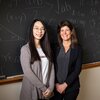 Jiawen Wu standing on left side, Eva Pomerantz on right, in front of a black board with mathematical formulas written all over it.